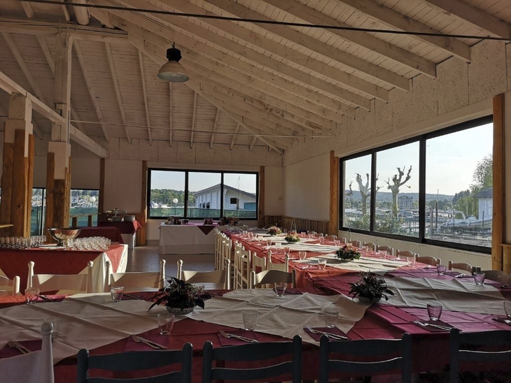 Blick in ein festlich gedecktes Restaurant mit großen Fenstern und Ausblick auf den Campingplatz.