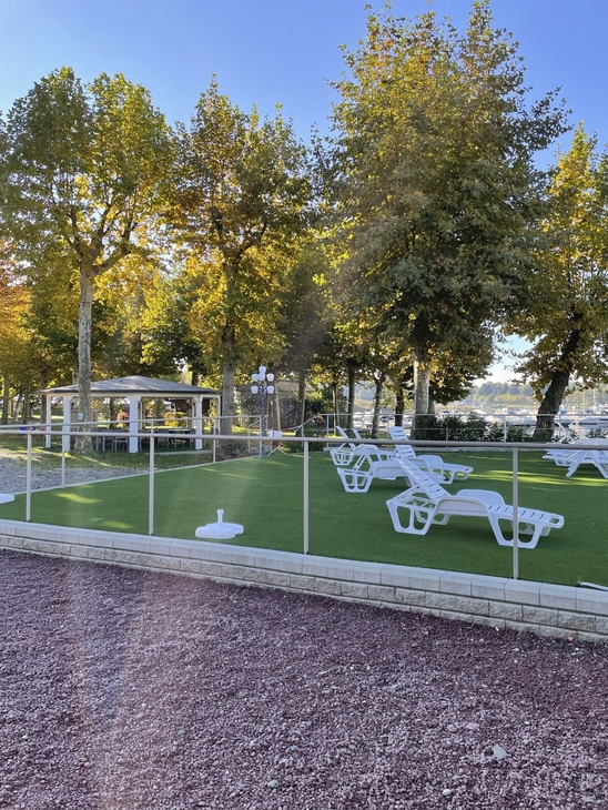 Liegestühle und Bäume auf einem Campingplatz bei sonnigem Wetter.