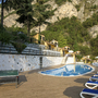 Sonnenterrasse mit Pool, Sonnenliegen und Tischtennisplatte vor Hügelkulisse.
