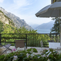 Terrasse mit Gartenmöbeln und Blick auf Berge und See.