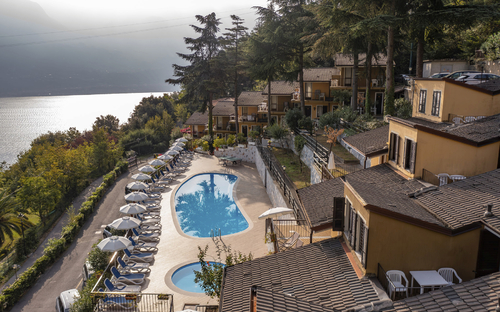 Panoramablick auf eine Hotelanlage mit Pool und umliegenden Bäumen am Hang.