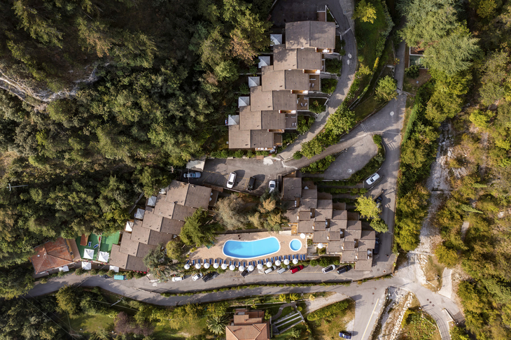 Luftaufnahme einer Ferienanlage mit Pool in einer bewaldeten Umgebung.