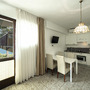 Helles Apartment mit Küchenzeile, Esstisch und Blick auf den See durch das Fenster.
