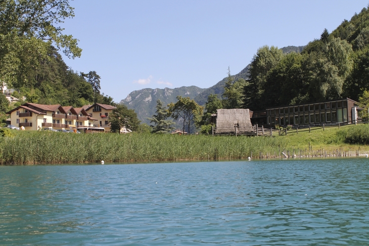 Uferansicht mit Häusern, Bäumen und Bergen am Ledro-See.