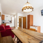 Essbereich mit Holztisch, rotem Sofa und Fernseher an der Wand.