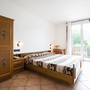 Helles Schlafzimmer mit Holzmöbeln, Doppelbett und Balkon mit Blick ins Grüne.