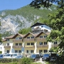 Gebäude im Alpenstil vor bewaldeten Bergen an einem sonnigen Tag.