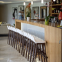 Moderne Hotelbar mit Holztresen und hohen Stühlen.