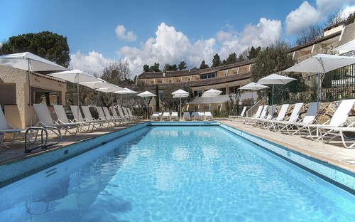 Poolansicht im Hotel La Vague in Saint-Paul-de-Vence mit Liegestühlen und Sonnenschirmen.