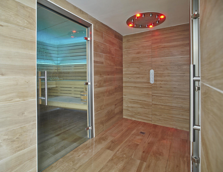 Innensicht einer modernen Sauna mit Holzwänden und Glastür.