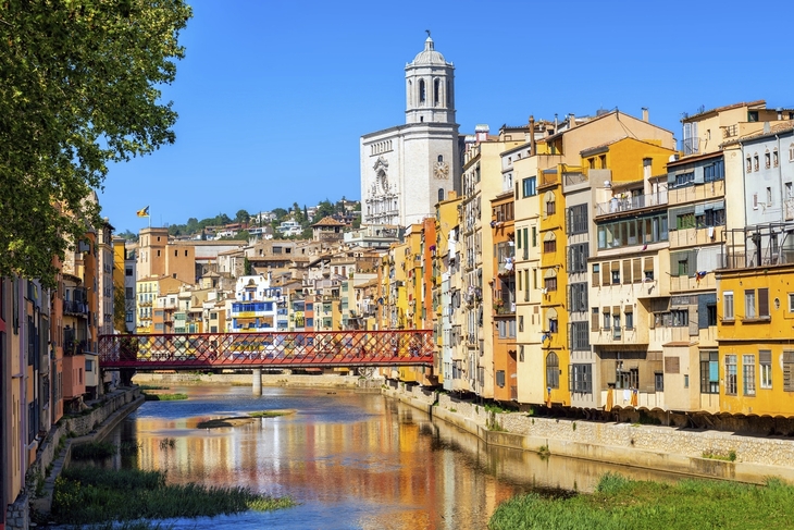 Bunte Häuser und Fluss in Girona, Katalonien mit Brücke und Kirche im Hintergrund.