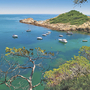 Küste der Costa Brava mit Booten in einer malerischen Bucht und grüner Vegetation.