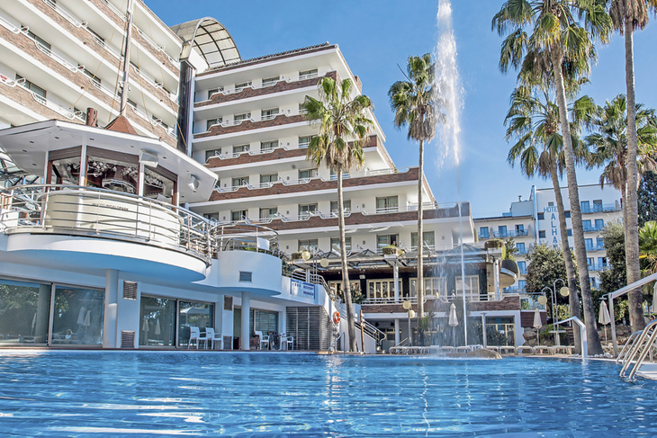 Hotel Indalo Park mit Pool und Palmen an der Costa Brava bei Sonnenschein