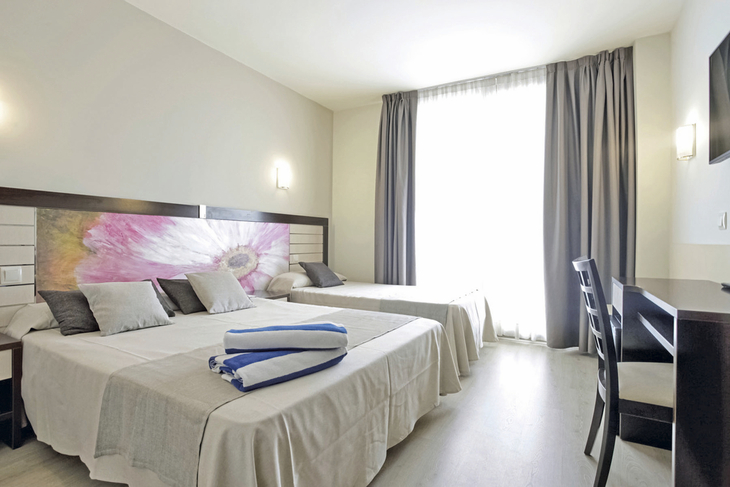 Helles Hotelzimmer mit zwei Betten und abstraktem Wandbild.