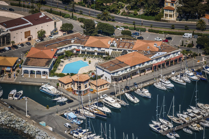 Luftaufnahme eines Hotels am Yachthafen von St. Raphael mit Pool und Segelbooten.