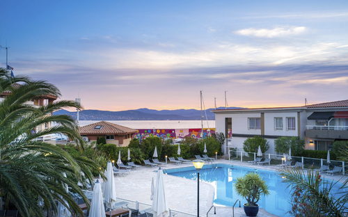 Hotelpool bei Sonnenuntergang mit Blick auf die Marina und die umliegenden Gebäude.