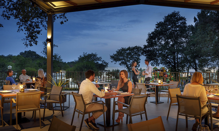 Gäste im Restaurant auf einer Terrasse am Abend unter freiem Himmel.