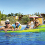 Familie genießt Freizeit im Pool mit aufblasbarer Matratze im Ferienresort.