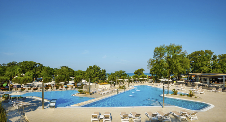 Poolbereich des Camping Maravea Resorts mit Liegestühlen und Bäumen im Hintergrund.