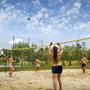 Menschen spielen Beachvolleyball auf einem sandigen Feld im Freien.