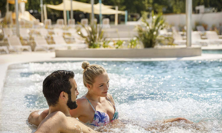 Paar entspannt im Pool mit sprudelndem Wasser im Resort.