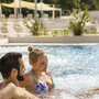 Paar entspannt im Pool mit sprudelndem Wasser im Resort.
