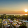 Luftaufnahme eines Campingplatzes mit Mobilheimen und Swimmingpool bei Sonnenuntergang.