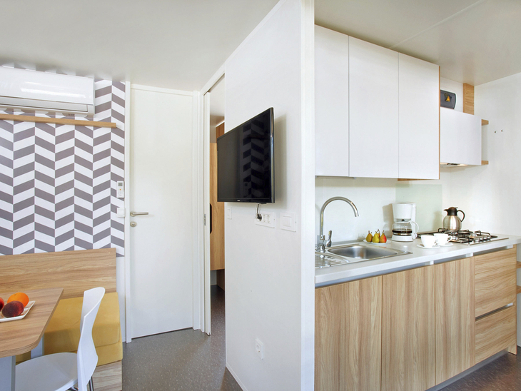 Kompakte, moderne Campingküche mit Essbereich und TV.