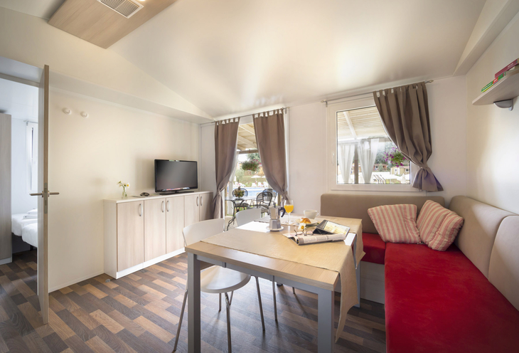 Innenansicht eines modernen Wohnraums mit Tisch, Sofa und Fernseher.