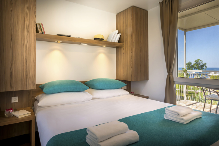 Moderne Hotellzimmer mit Doppelbett und Aussicht auf Balkon mit Meerblick.