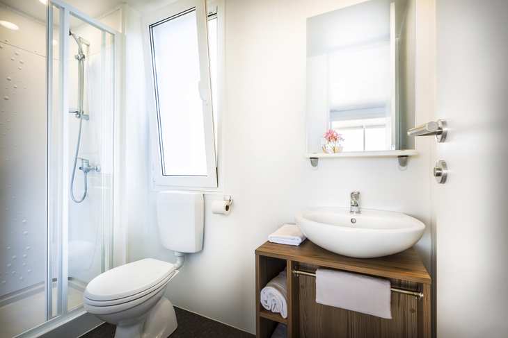Modernes Badezimmer mit Dusche, WC, Waschbecken und Fenster.