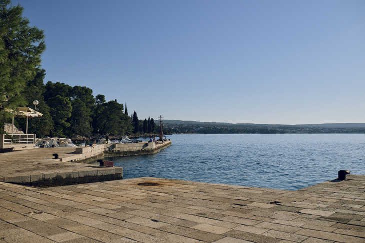 Küste von Malinska auf der Insel Krk, Kroatien, mit klarem Himmel und ruhigem Meer.