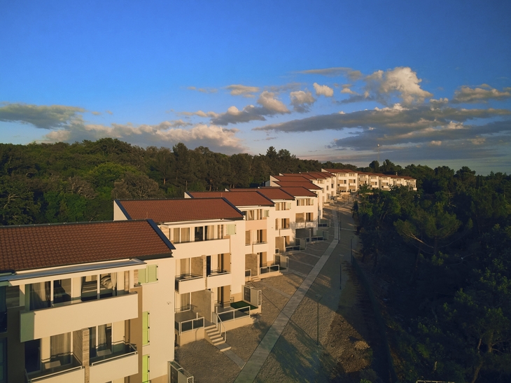 Moderne Wohnhäuser in Reihenanordnung unter blauem Himmel.