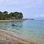 Strand bei Malinska, Krk mit klarem Wasser und Kajakfahrern.