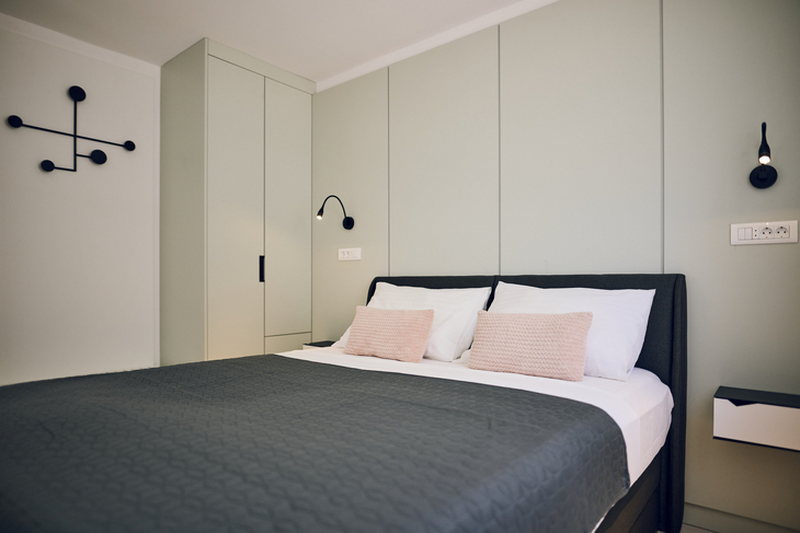 Modernes Schlafzimmer mit einem Doppelbett, Kissen und Wandleuchten.