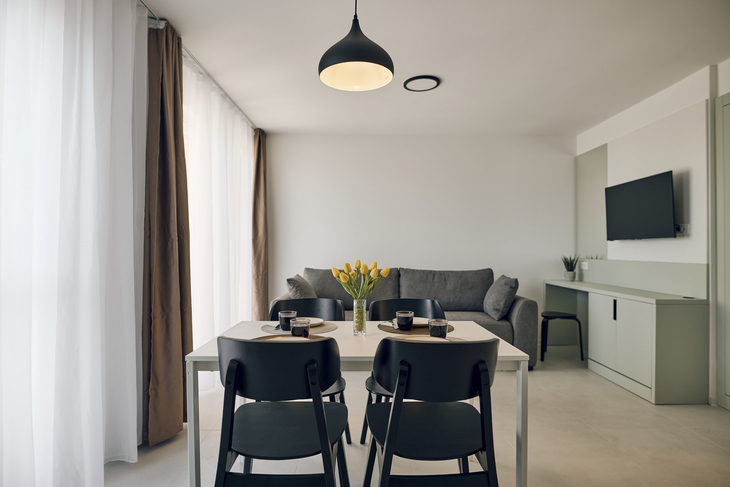 Modernes Wohnzimmer mit Esstisch, Sofa, Fernseher und Küchenecke.