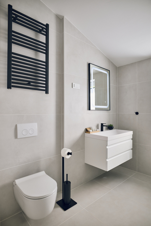 Modernes Badezimmer mit weißem Interieur, Wandspiegel und Handtuchheizkörper.