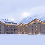 Aparthotel im Winter mit schneebedeckten Bergen im Hintergrund.