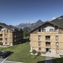 Zwei moderne Gebäude in alpiner Landschaft mit Bergen im Hintergrund.