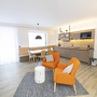 Wohnzimmer mit modernen Möbeln, Esstisch und offener Küche im Hintergrund.
