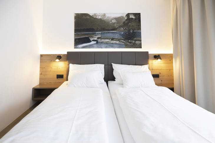 Zwei Einzelbetten in modernem Hotelzimmer mit Wandkunst.