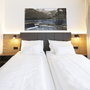 Zwei Einzelbetten in modernem Hotelzimmer mit Wandkunst.