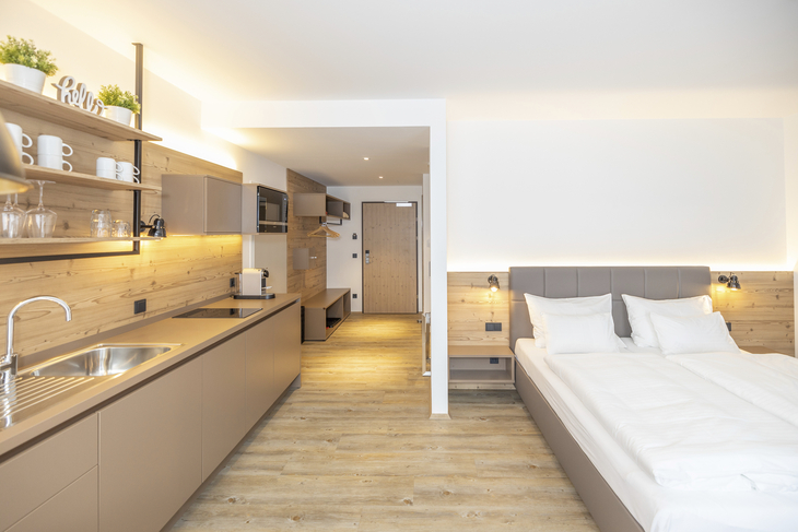Moderne Ferienwohnung mit Küche und Doppelbett in Holzoptik.