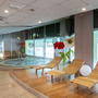Wellnessbereich mit Liegestühlen und Whirlpool, umgeben von Glaswänden.