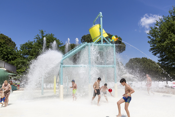 Kinder spielen im Wasserpark mit Wasserspielgeräten und Spritzwasser.