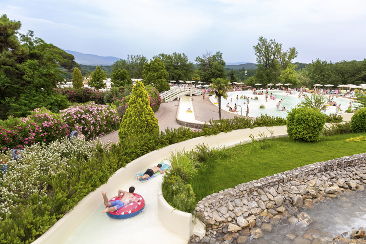 Wasserpark mit Menschen auf einer Rutsche im Norcenni Girasole Village, umgeben von Natur.