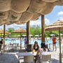 Terrasse am Pool mit Tischen und Strohschirmen im Norcenni Girasole Village, Toskana.