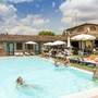 Menschen entspannen sich an einem sonnigen Pool in einer Ferienanlage.