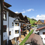 Mehrstöckiges Hotel in Alpenumgebung mit Balkonen und blumengeschmückten Fenstern.