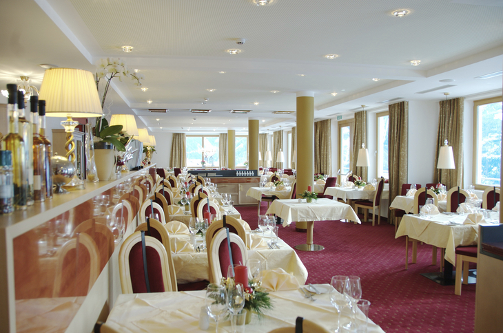 Eleganter Speisesaal mit gedeckten Tischen und rotem Teppichboden.